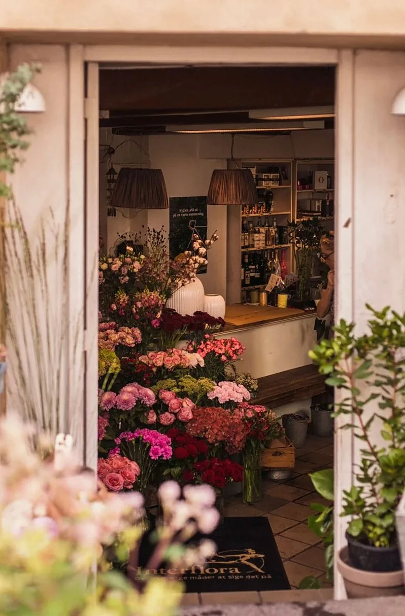 Charming entrance to a flower shop filled with vibrant roses and floral arrangements.